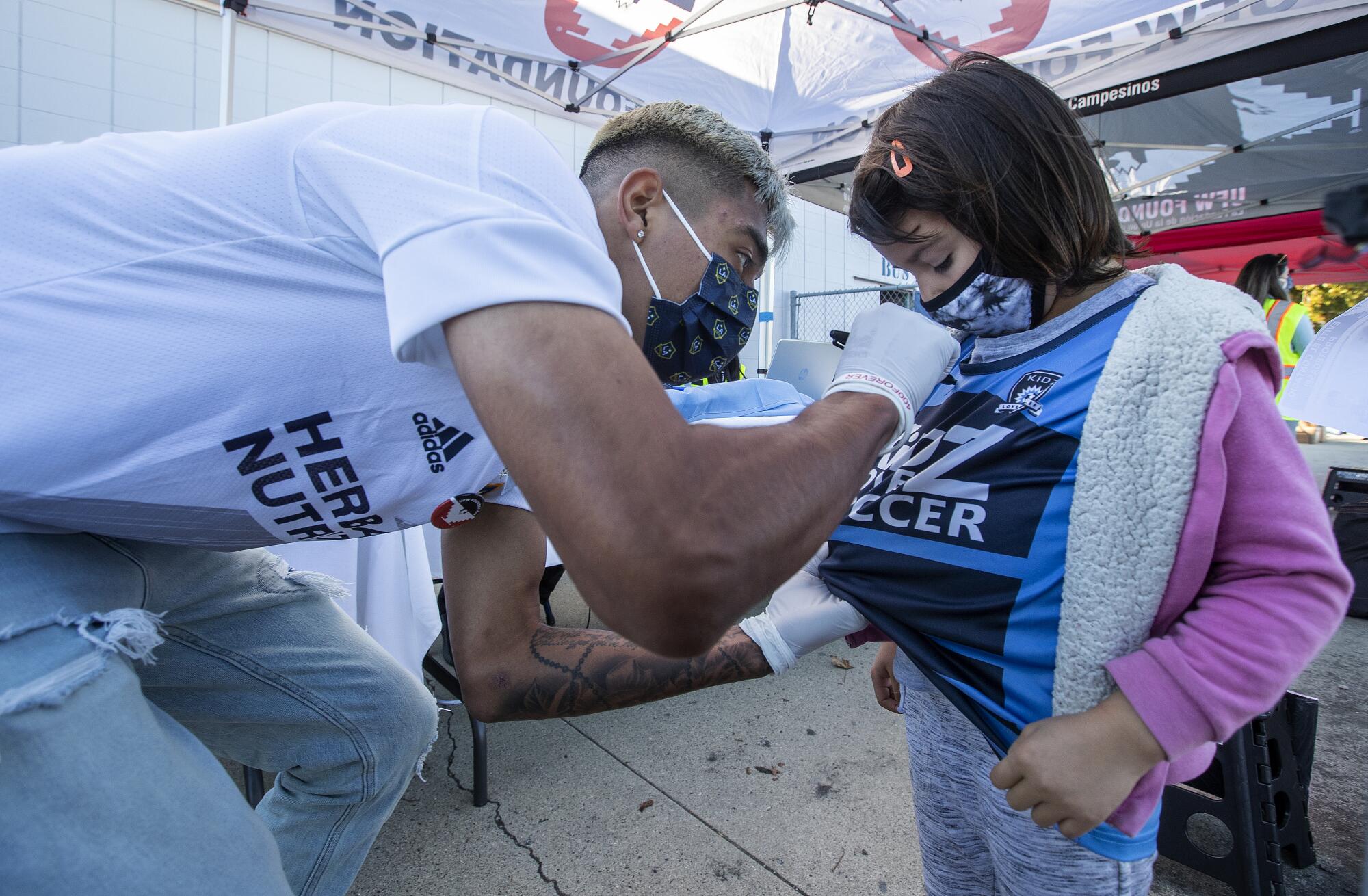 Los Angeles Galaxy soccer player Julian Araujo signs the shirt of Lompoc resident Camelia Rosales.