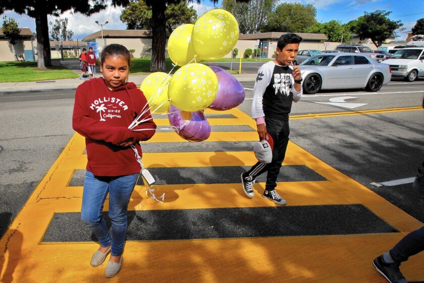 Leslie Corrales, 10, left, brings balloons to a memorial near where three 13-year-old girls were killed by a hit-and-run driver on Halloween. For some, the deaths are a tragic case in point of how Proposition 47 could be considered a risky experiment.