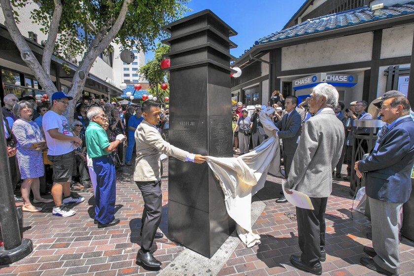 Filmmaker Jeffrey Gee Chin, left, and sculptor Miles Endo, holding the far end of veil, reveal an 8-foot-tall steel lantern in Little Tokyo's Japanese Village Plaza. The monument is dedicated to the Japanese-born late civil rights activist Sei Fujii.