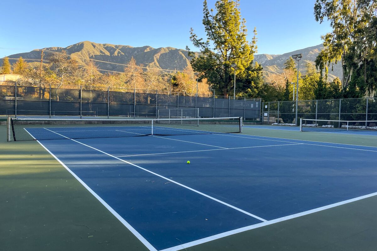 A tennis court with mountains and trees in the background
