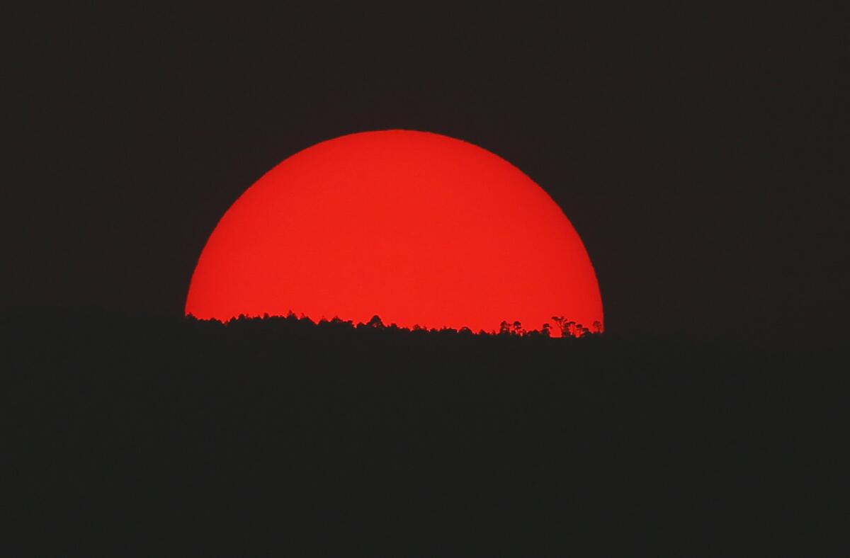 Teñido de rojo por una espesa nube de humo y contaminación, el sol se pone sobre las montañas de la Ciudad de México, el lunes 13 de mayo de 2019. (AP Foto/Marco Ugarte)