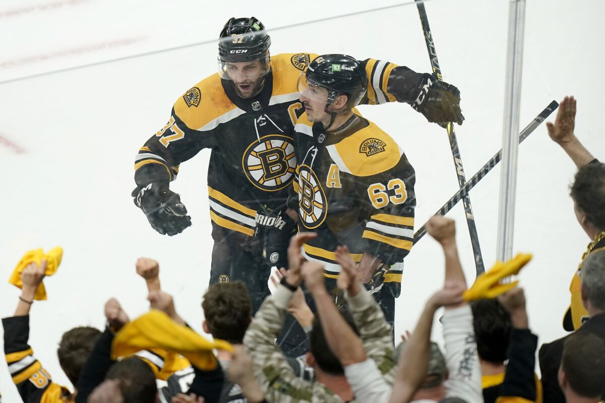 Boston Bruins' Patrice Bergeron, top left, celebrates with Brad Marchand, right, after Marchand scored in the third period of Game 4 of an NHL hockey Stanley Cup first-round playoff series against the Carolina Hurricanes, Sunday, May 8, 2022, in Boston. (AP Photo/Steven Senne)