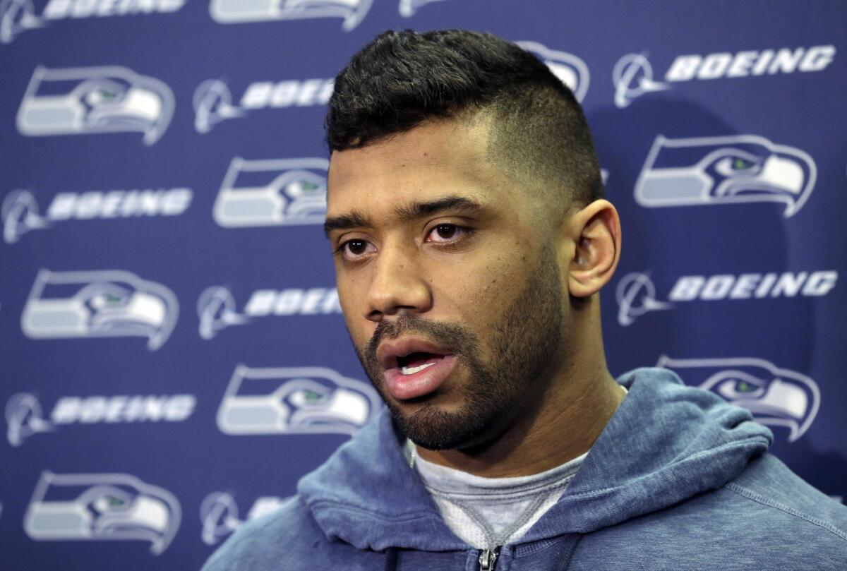 Seattle Seahawks quarterback Russell Wilson talks to reporters outside the locker room at team headquarters.