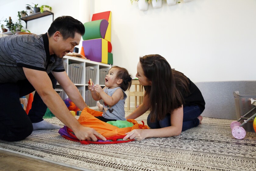 A couple get down on the floor to play with their baby daughter, center. 