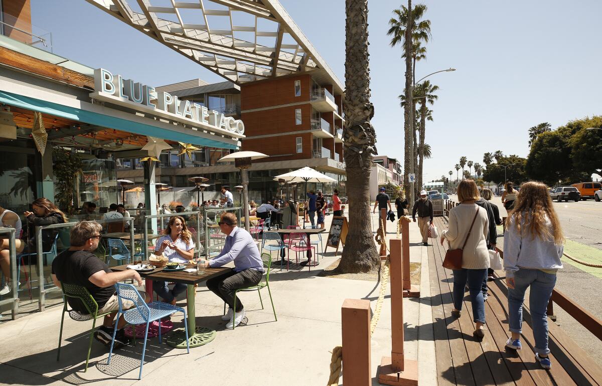 People dining outdoors near a sidewalk. 