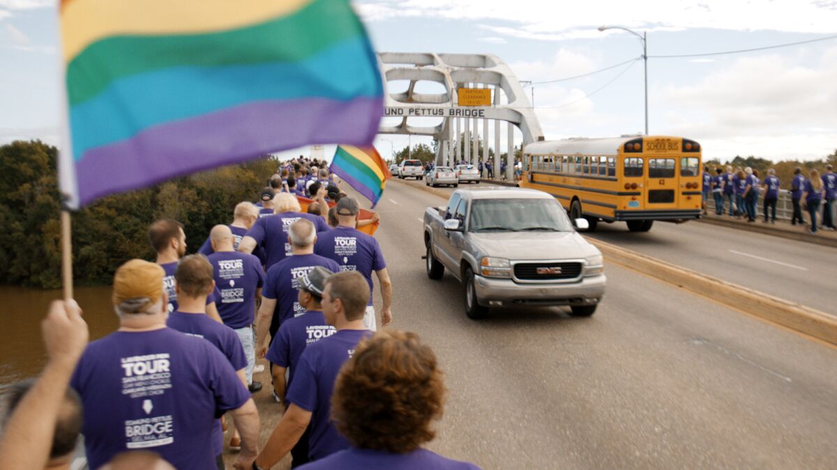 People in purple shirts wave rainbow flags along the Edmund Pettus Bridge in Selma, Ala., in the documentary "Gay Chorus Deep South."