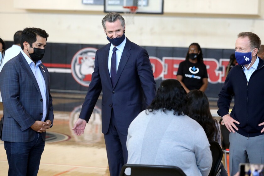 LOS ANGELES, CA - MAY 27: Governor Gavin Newsom, center, shown with form far left, Reps. Jimmy Gomez (D-Los Angeles), and Austin Beutner, Superintendent of the Los Angeles Unified School District, visit a vaccination site to unveil a $116.5 million COVID-19 vaccine incentive plan, including cash prizes and gift cards at Esteban Torres High School on Thursday, May 27, 2021 in Los Angeles, CA. New efforts by the state to encourage more Californians - especially those in communities that have been hit hardest by the pandemic - to get vaccinated. (Gary Coronado / Los Angeles Times)