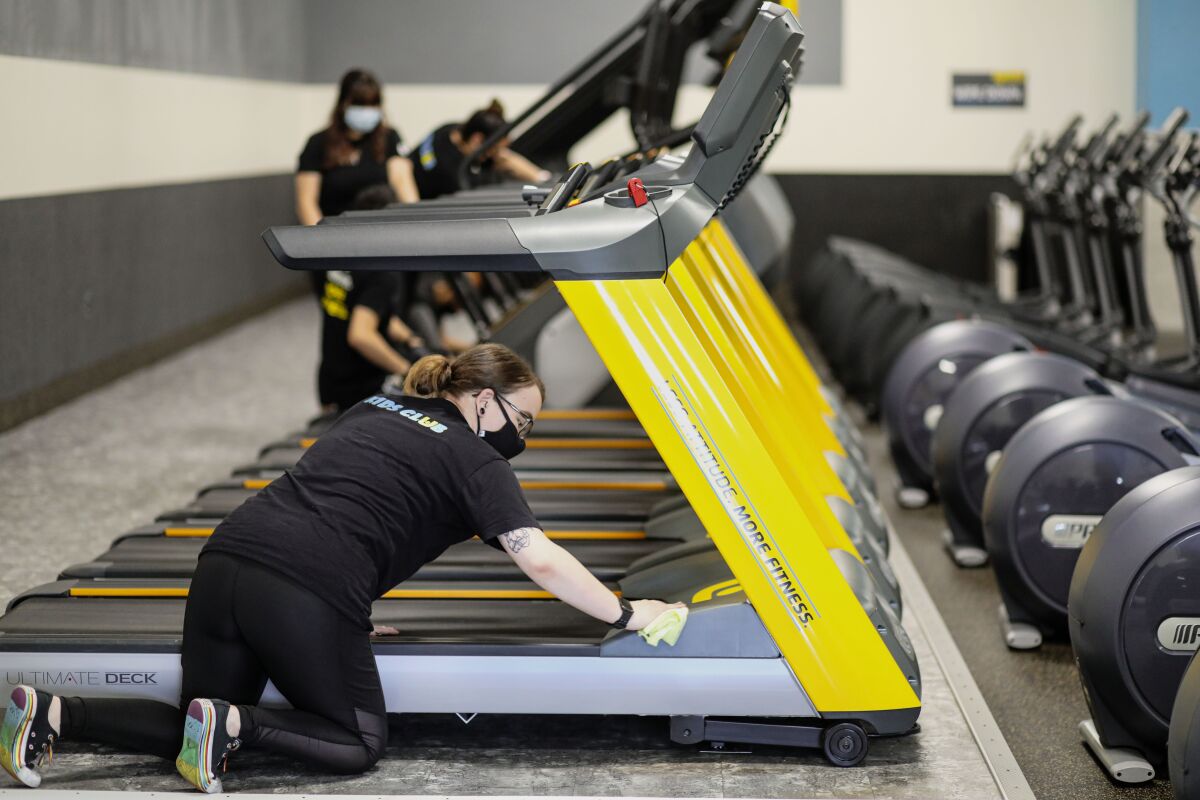 Employee Audry Andrade cleans treadmill machines at Chuze Fitness in Chula Vista 