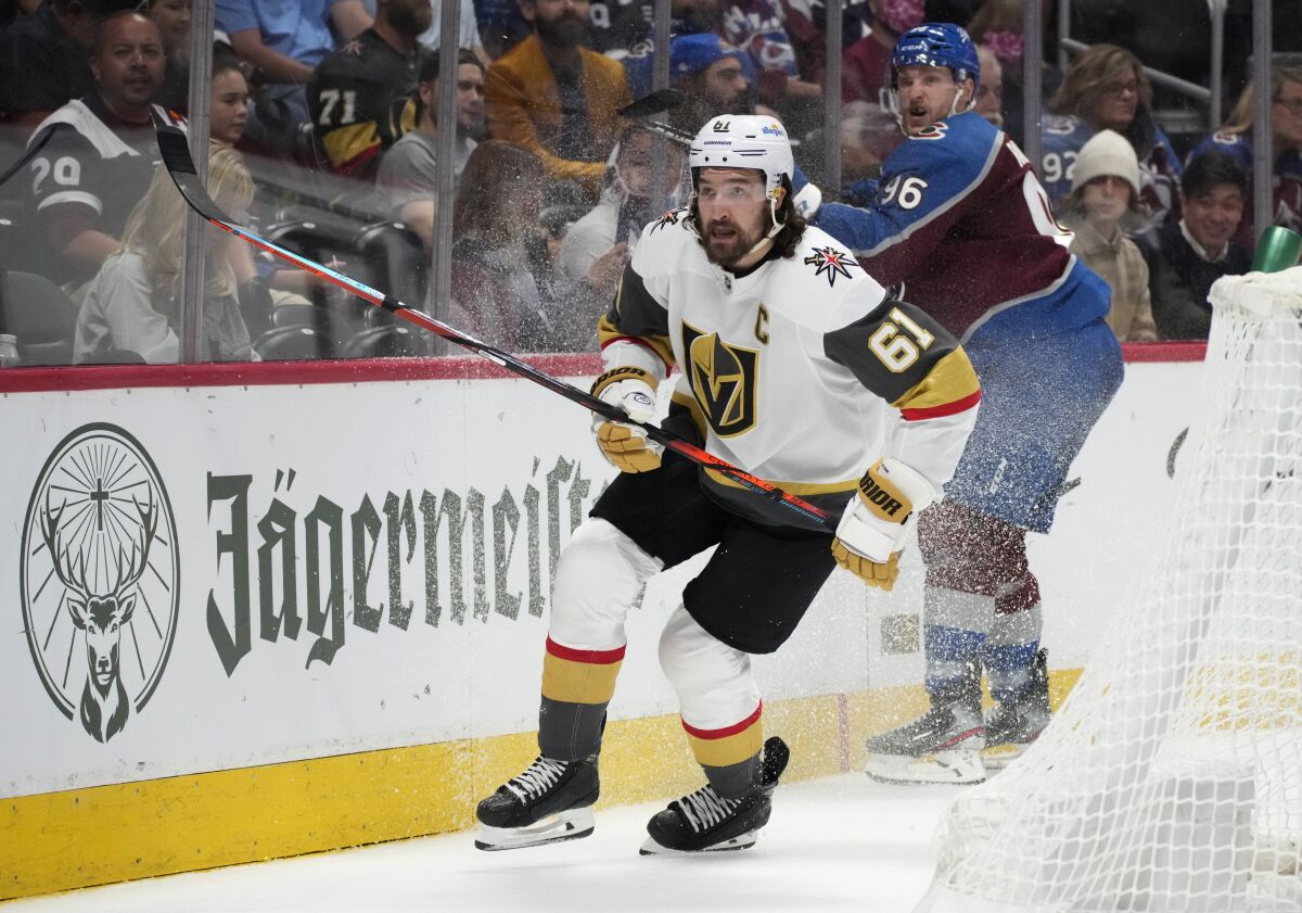 Vegas Golden Knights right wing Mark Stone, front, pursues the puck after checking Colorado Avalanche right wing Mikko Rantanen during the second period of Game 5 in an NHL hockey Stanley Cup second-round playoff series Tuesday, June 8, 2021, in Denver. The Golden Knights won 3-2 in overtime. (AP Photo/David Zalubowski)