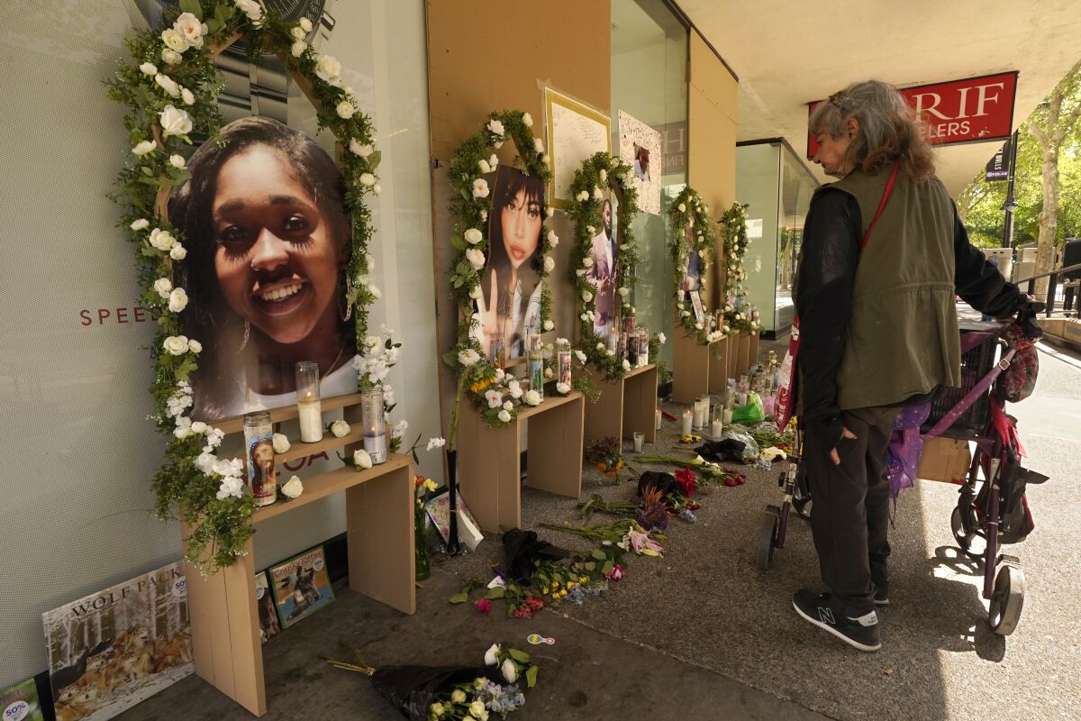 A passerby pauses at a memorial for the six people killed in mass shooting in Sacramento, Calif., on Wednesday, April 6, 2022. Multiple people were killed and injured in the shooting that occurred Sunday, April, 3, 2022. (AP Photo/Rich Pedroncelli)