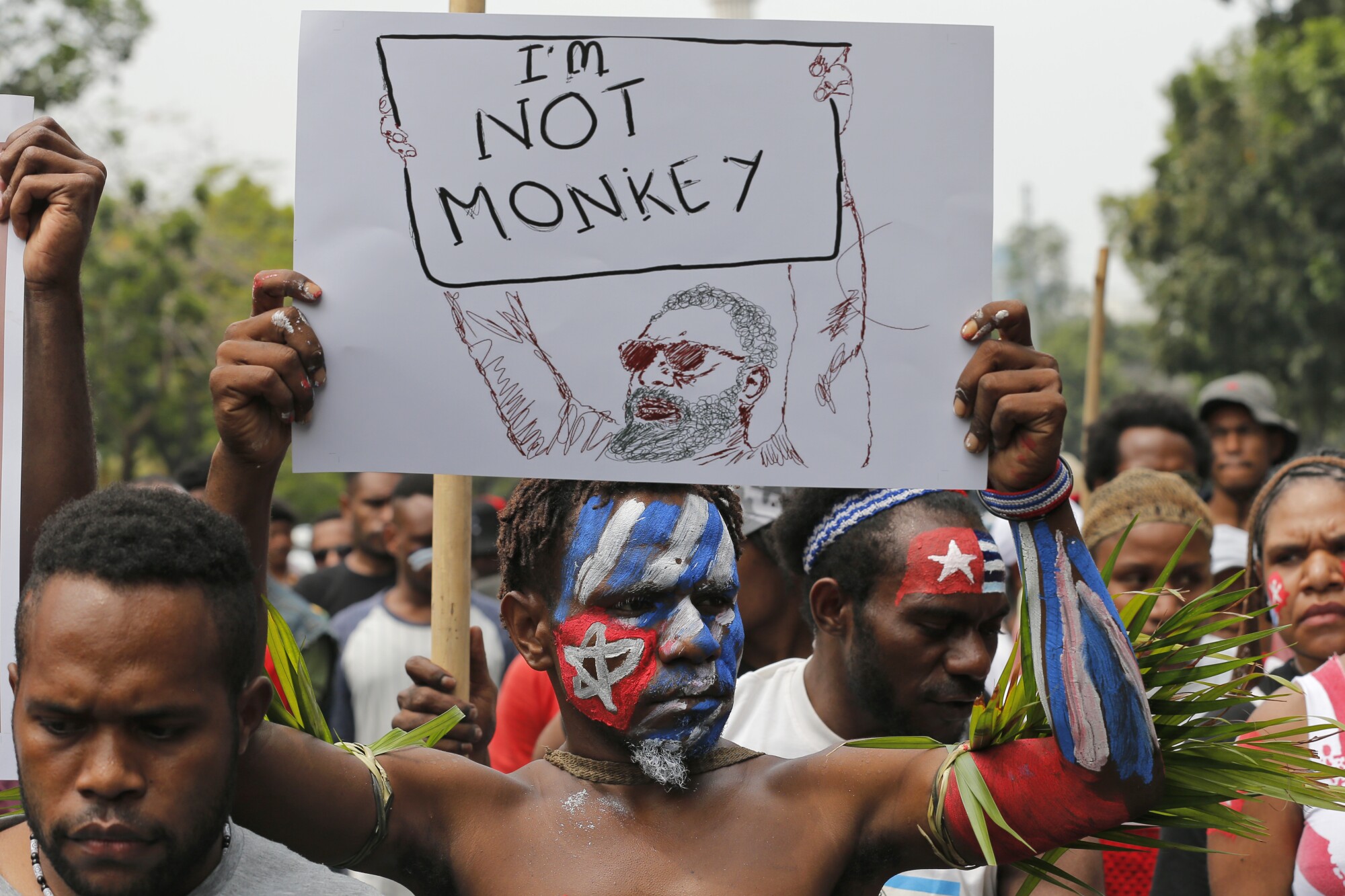 Papuan student, his face painted with the colors of the separatist Morning Star flag, holds a poster during a rally.