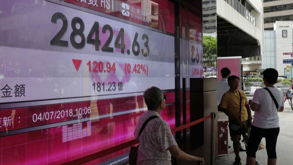 People walk past a bank electronic board Wednesday showing the Hong Kong share index at the Hong Kong Stock Exchange. Asian shares closed moderately after U.S. stocks snapped a three-day winning streak the day before.