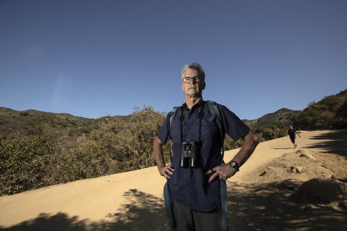 Gerry Hans, binoculars around his neck, stands on the Brush Canyon Trail in Griffith Park.