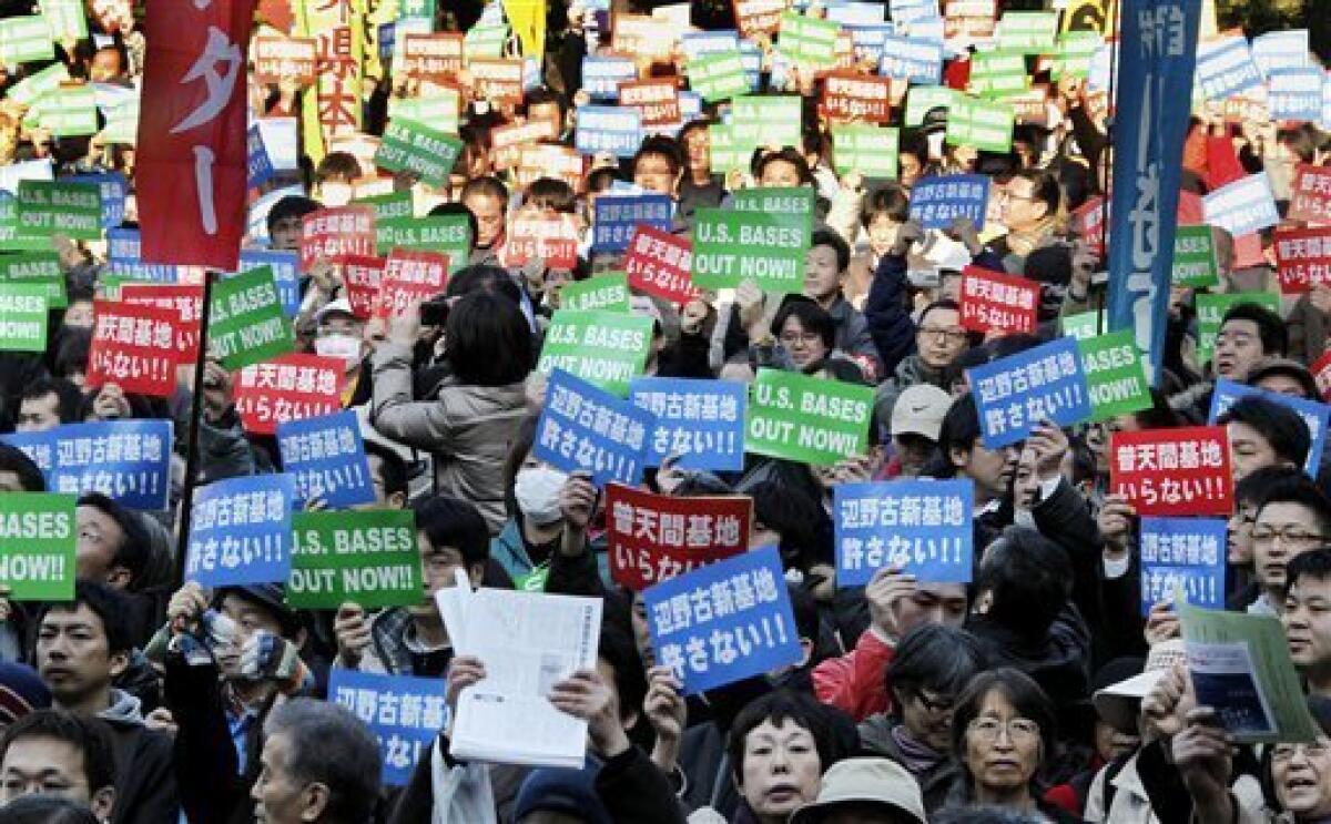 Demonstrators hold up anti-U.S. bases slogans as some 6,000 people gather at a rally protesting against a U.S. Marine base stationed on the southern island of Okinawa, in Tokyo Saturday, Jan. 30, 2010. Japanese Prime Minister Yukio Hatoyama said Friday he would decide by the end of May on where to relocate the U.S. Marine Airfield Futenma in Okinawa that has strained ties between the nations. The slogans written in Japanese read: "We don't need Futenma base," in red, and "We refuse new Henoko base," in blue. (AP Photo/Koji Sasahara)