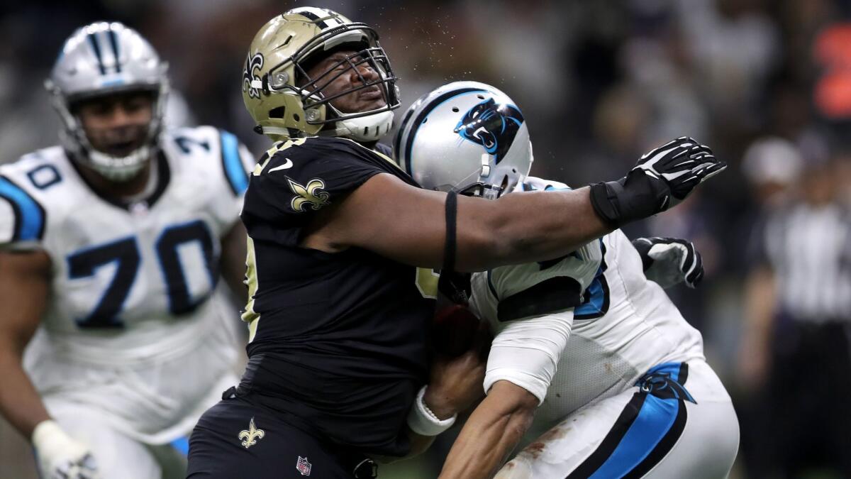 A tackle by New Orleans Saints defender David Onyemata, left, shakes up Carolina Panthers quarterback Cam Newton.