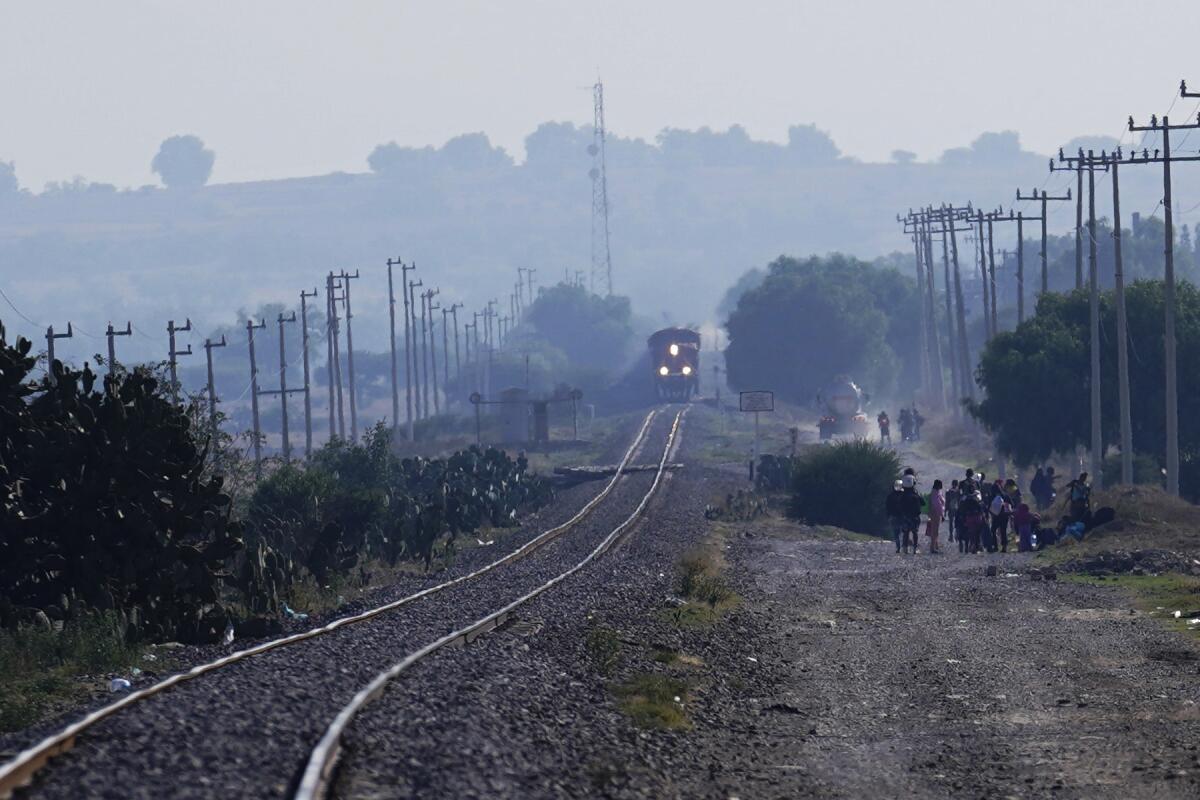 ARCHIVO - Un tren de carga circula mientras los migrantes esperan la oportunidad de subirse 