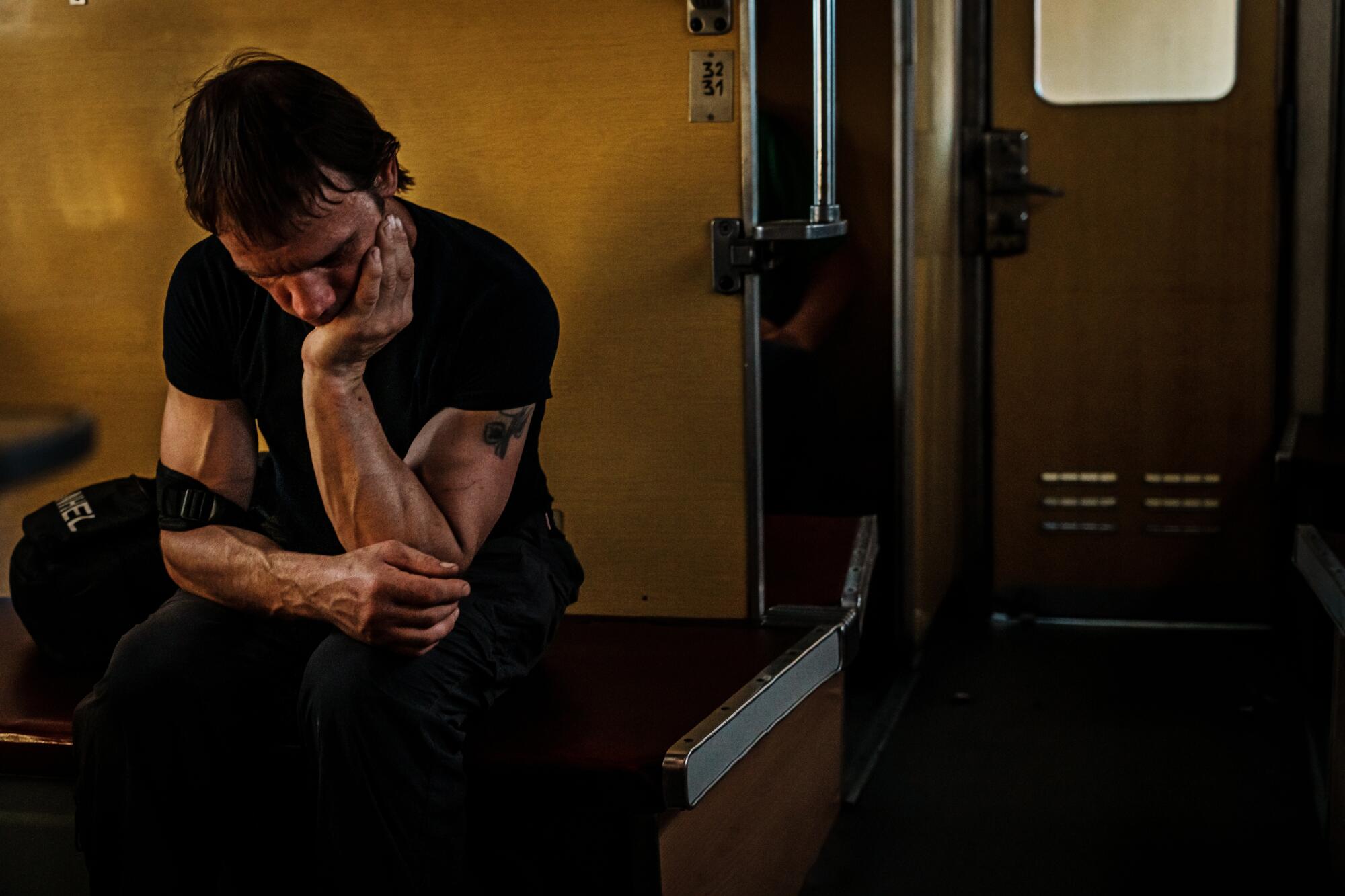 A man crouches on a train.