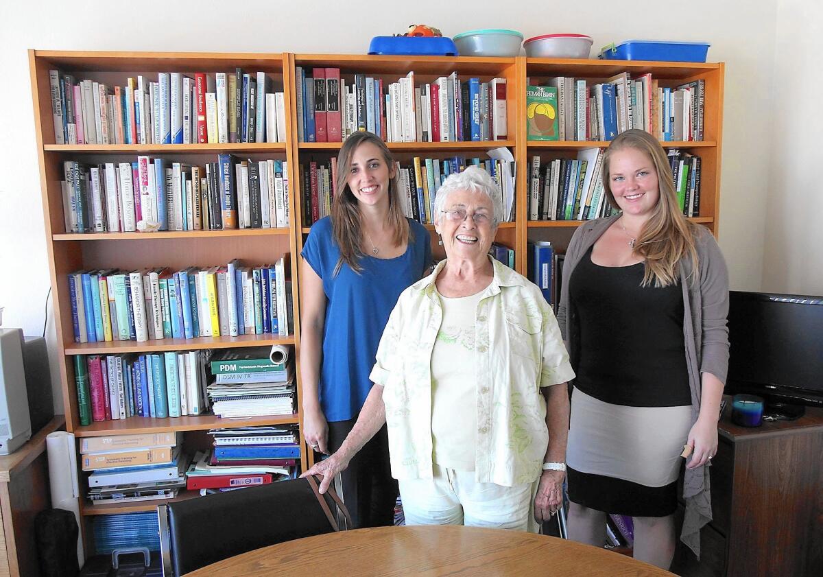 Marianna Thomas, the woman behind the Living Success Center, is flanked by Kendall Hopkins, left, and Christina Kennedy in the office and library of the Costa Mesa facility.
