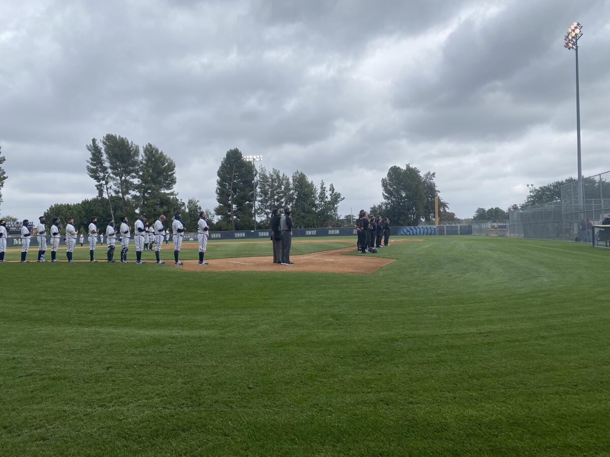 Birmingham and JSerra players stand for the national anthem on a cloudy Tuesday in Lake Balboa.