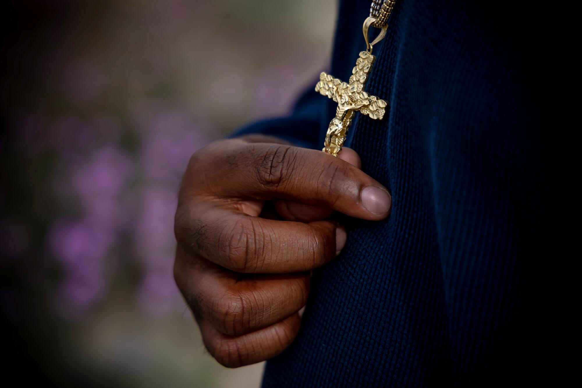 A hand holds a cross.