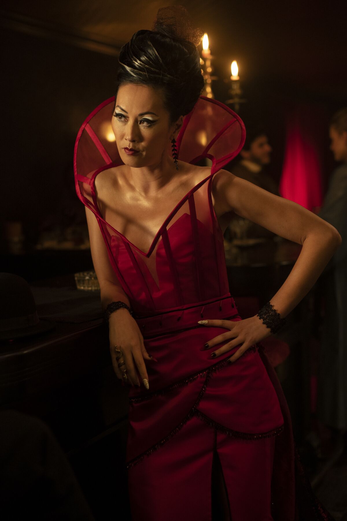 A woman in a red dress leans against a table.