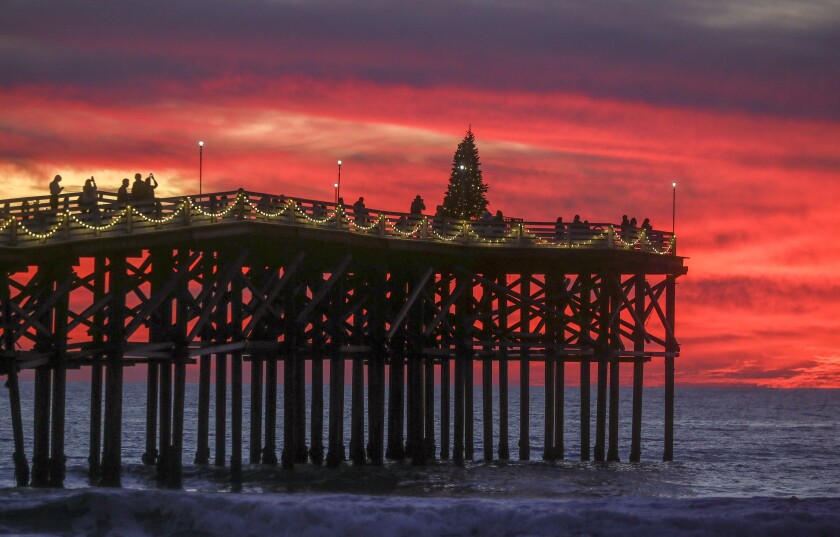 People take photos of Crystal Pier's  Christmas tree at sunset  in this 2019 file photo.