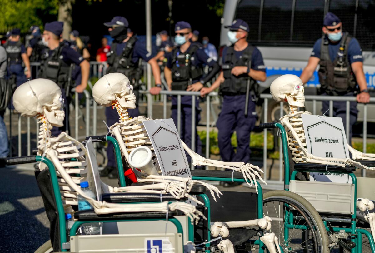 Medical stuff push skeletons in wheel chairs protesting in front of the Chancellery in Warsaw, Poland, Saturday, Sept.11, 2021. (AP Photo/Czarek Sokolowski)