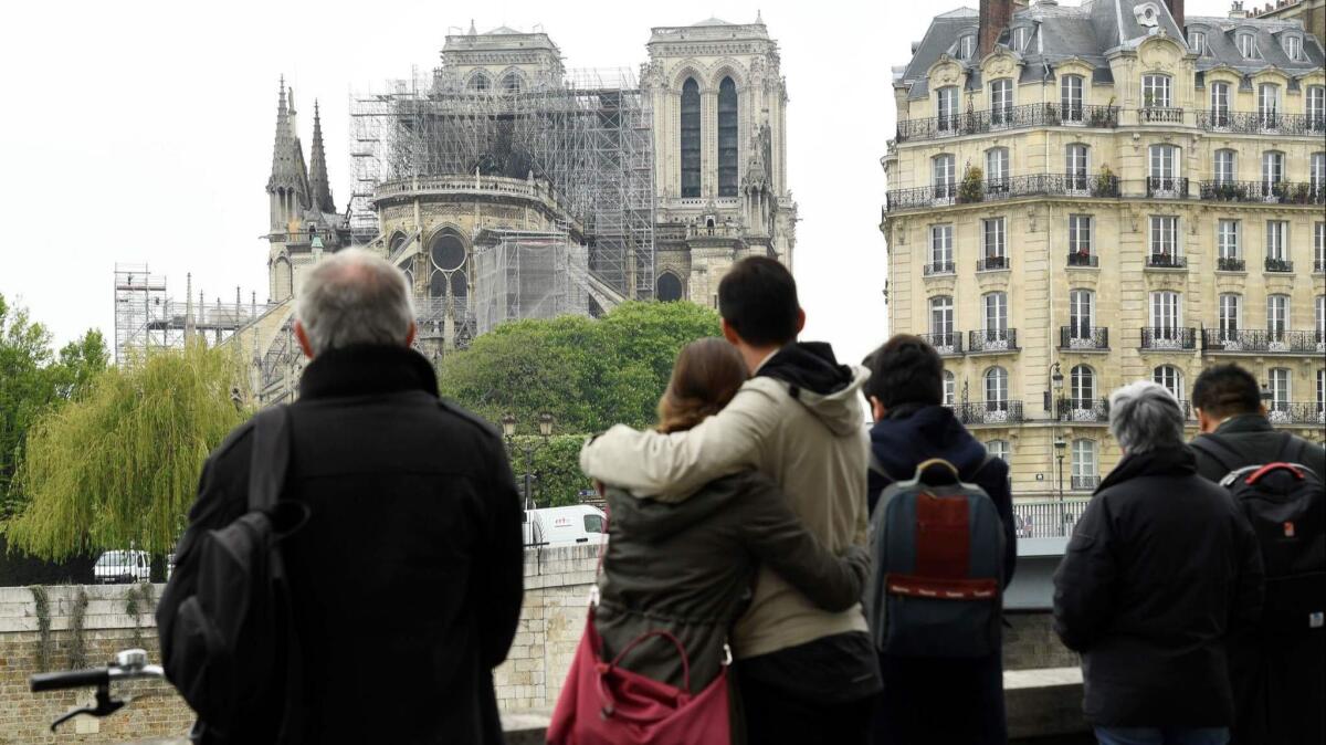 People hug while looking at Notre Dame de Paris on Tuesday.