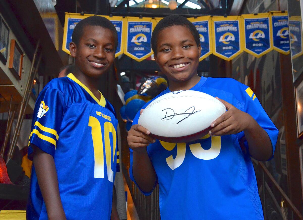 Kingston Crockett and brother Kenny show off their football signed by Mr. Irrelevant Desjuan Johnson on Monday.