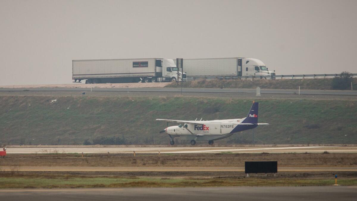 A FedEx plane taxis on the runway adjacent to Highway 99 at the Visalia Municipal Airport.