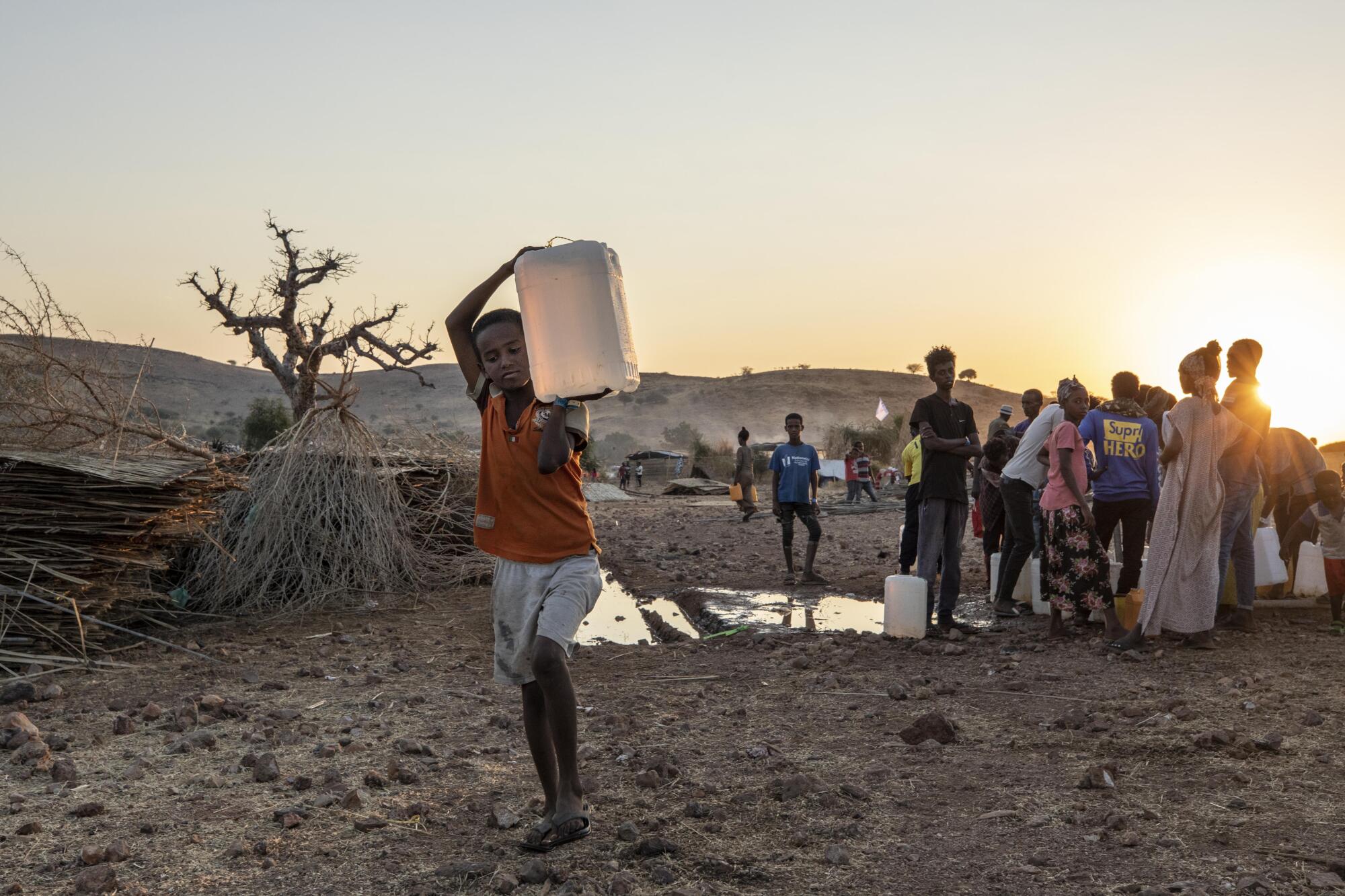 A Tigray boy who fled the conflict in Ethiopia's Tigray region, carries water, at a refugee camp in eastern Sudan.