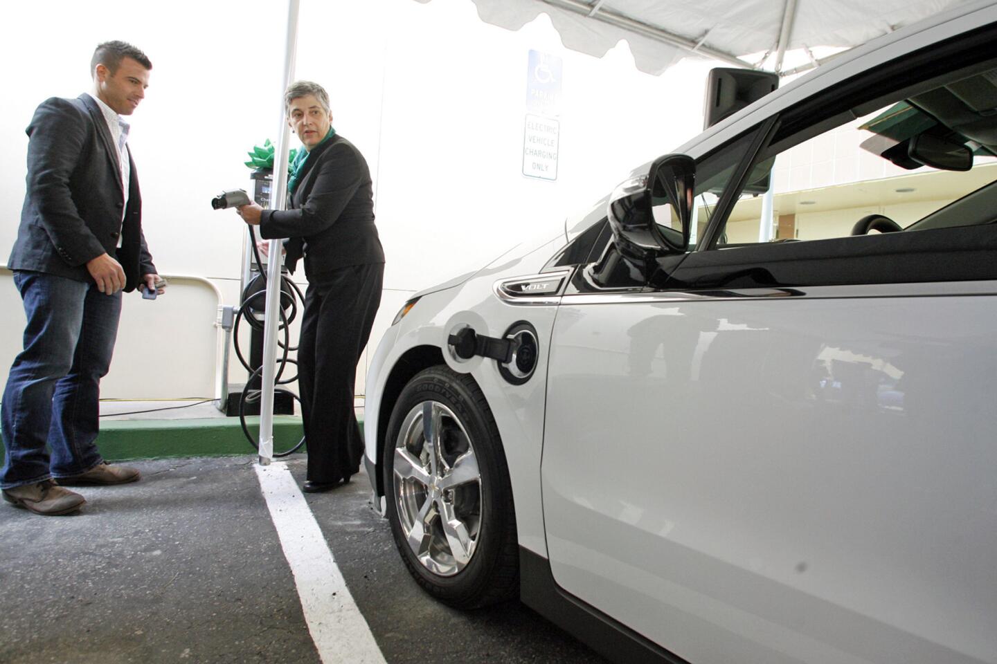 Shad D. Balch from General Motors Environment & Energy Policy and Communications, left, and Lynn C. Kronzek charge the Chevy Volt, an electric-powered vehicle, during a ribbon cutting ceremony at Burbank Town Center on Thursday, December 1, 2011. 11 electric charging vehicle stations will be spread throughout the city. The project was sponsored by Burbank Water and Power and the charging vehicle stations were given to the city by U.S. Department of Energy.