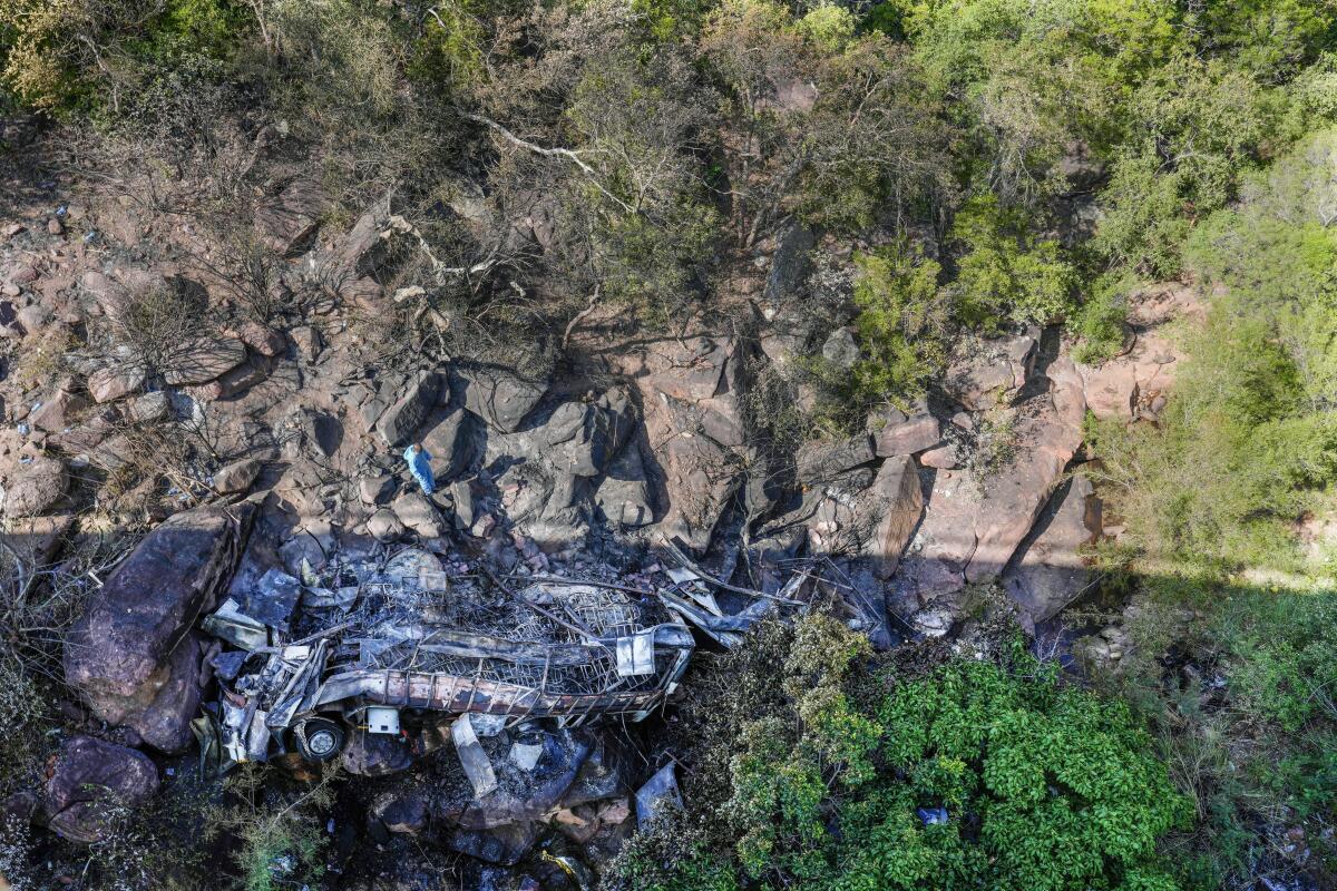 The burned wreckage of a bus in a ravine.