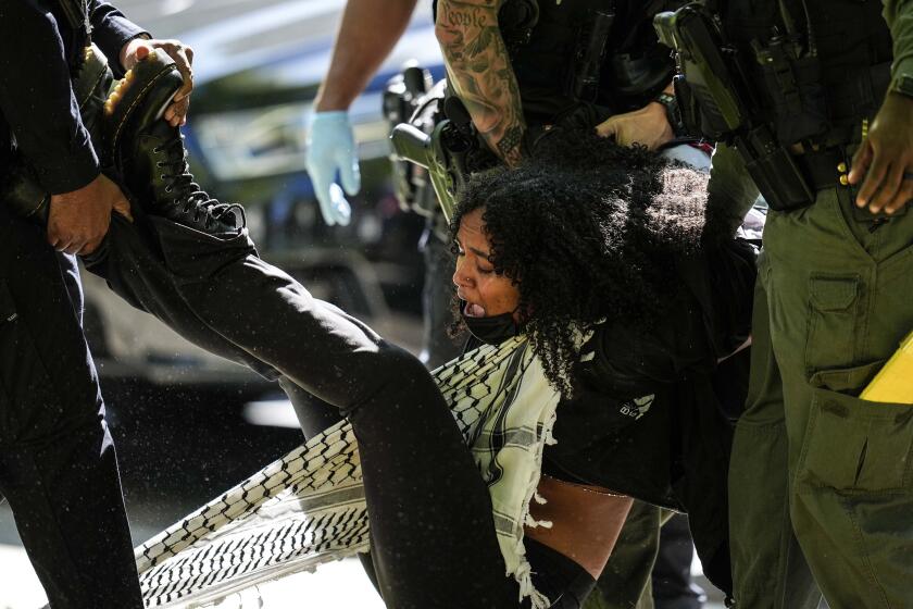 Autoridades detienen a una manifestante en el campus de la Universidad Emory durante una manifestación propalestina, el jueves 25 de abril de 2024, en Atlanta. (AP Foto/Mike Stewart)