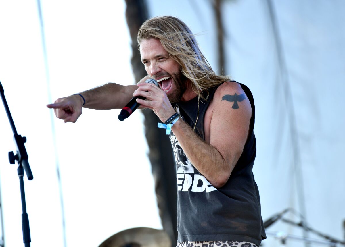 A man with long blond hair sings onstage
