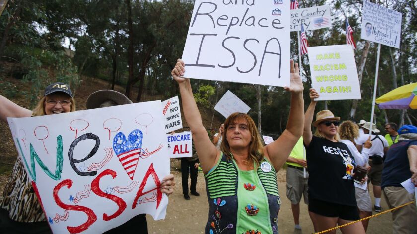 Costa del Sol of Vista holds an anti-Congressman Darrell Issa sign next to a Issa supporter during one of last year's weekly rallies outside the congressman's office in Vista.