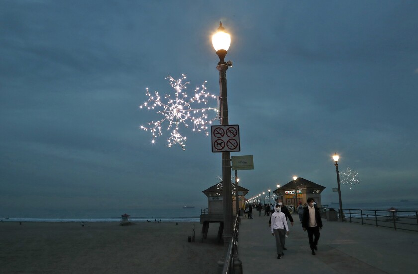 Dark skies roll in Wednesday as the Christmas snowflake lights turn on at the Huntington Beach Pier.