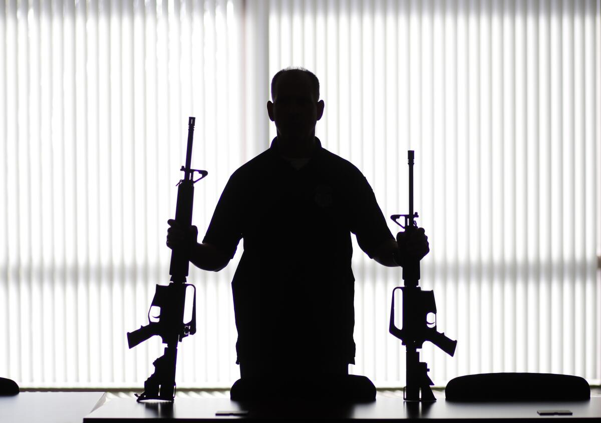 In this 2017 photo, an ATF agent poses with homemade rifles, or "ghost guns," at an ATF field office in Glendale, Calif.