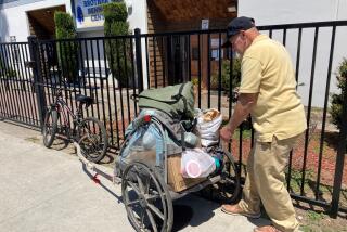 Irving Manuel checks food he loaded onto his cart Tuesday morning outside the Brother Benno's Center in Oceanside.