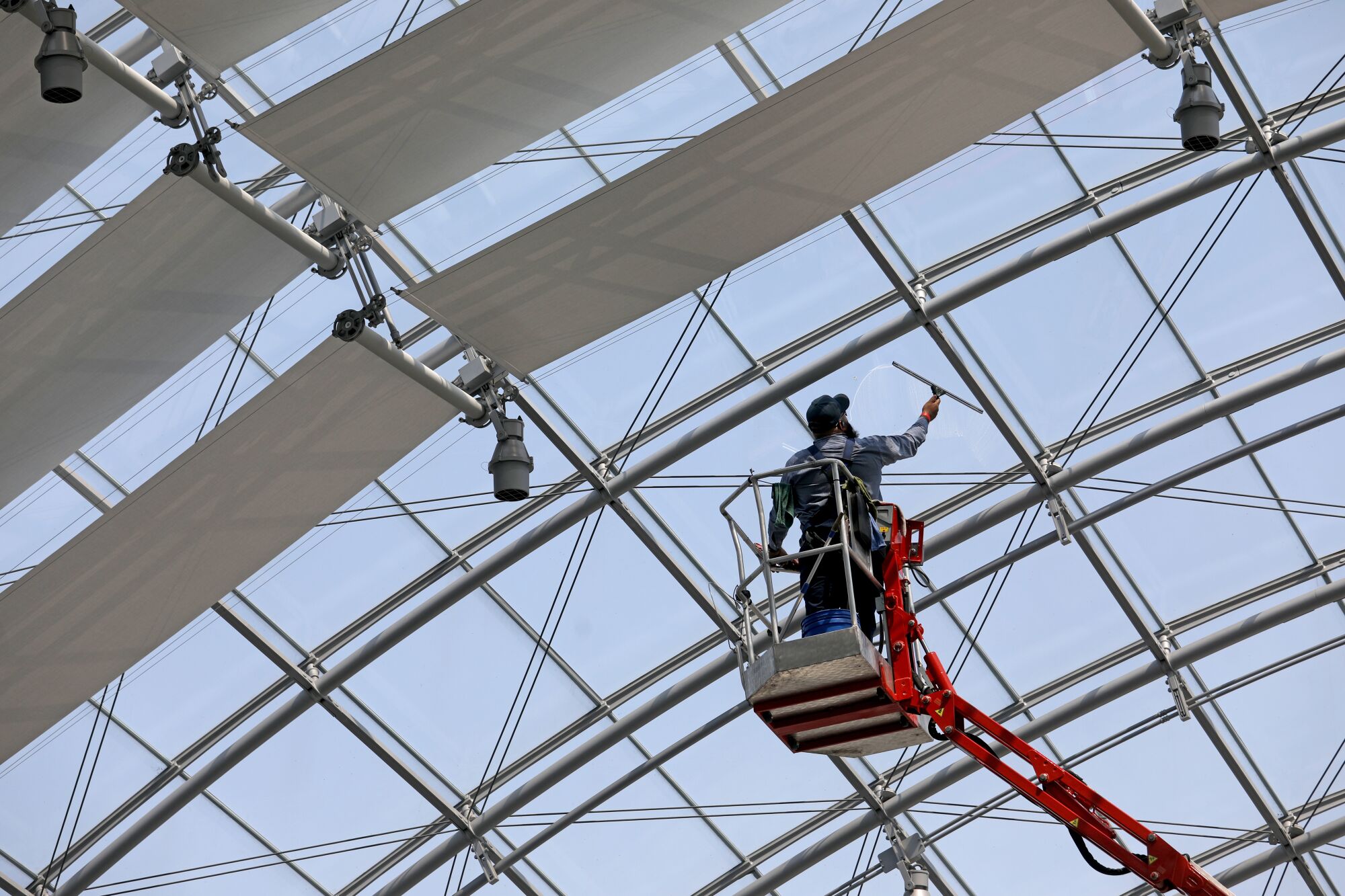 Jaime Vazquez, maintenance, cleans the glass dome covering the Dolby Family Terrace on the sphere