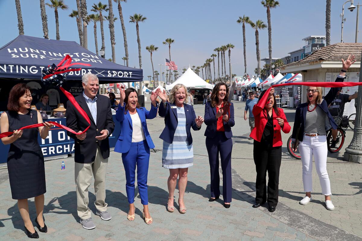 Huntington Beach Mayor Kim Carr, third from right, does the honor of cutting a ceremonial ribbon.