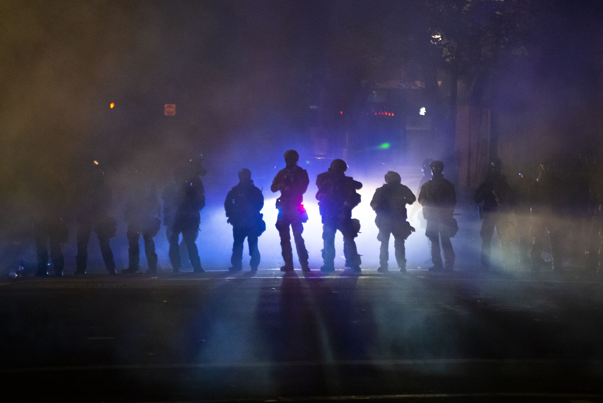 Federal officers walk through tear gas while dispersing a crowd at Mark O. Hatfield U.S. Courthouse in Portland, Ore.