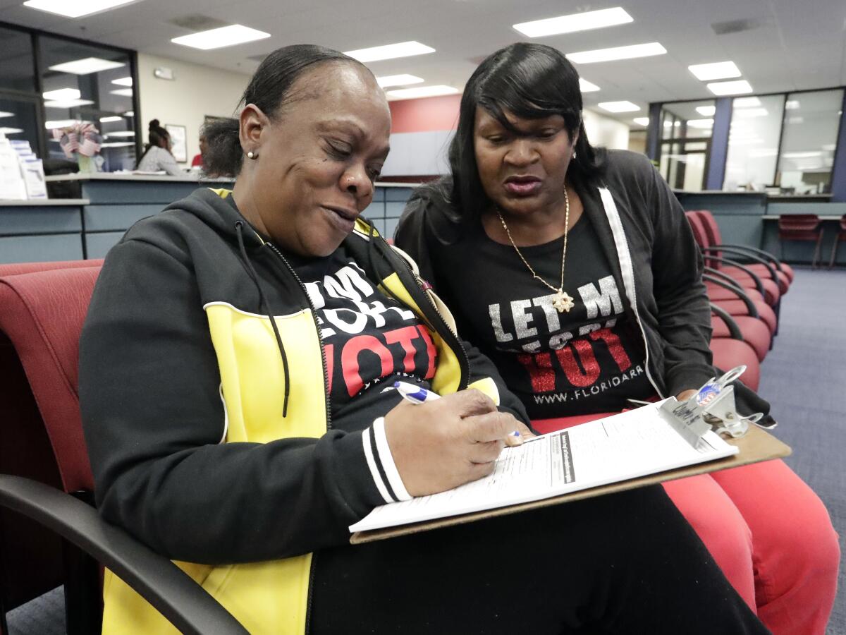 Gale Buswell watches her friend, former felon Yolanda Wilcox, fill out a voter registration form in Orlando, Fla., on Jan. 8.