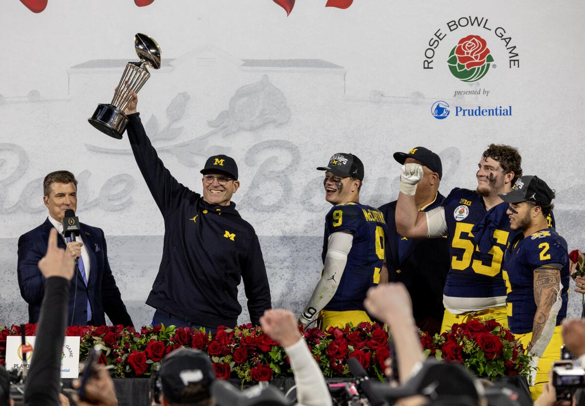 Michigan coach Jim Harbaugh holds the Rose Bowl trophy after the Wolverines' win over Alabama.