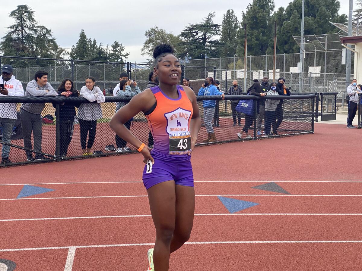 Junior Ta'Ahjah Fann stands on a track with onlookers behind her