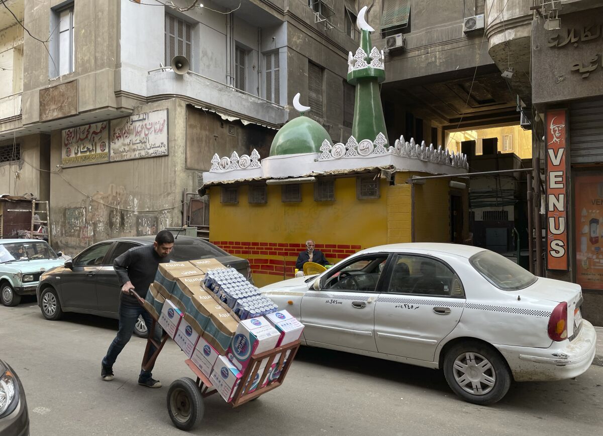 A vendor pushes his trolly in front of a mosque in Cairo, Egypt, Saturday, Feb. 25, 2023. (AP Photo/Amr Nabil)