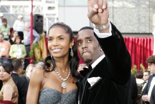 Kim Porter wears a gown as she poses next to Sean 'Diddy' Combs on a red carpet