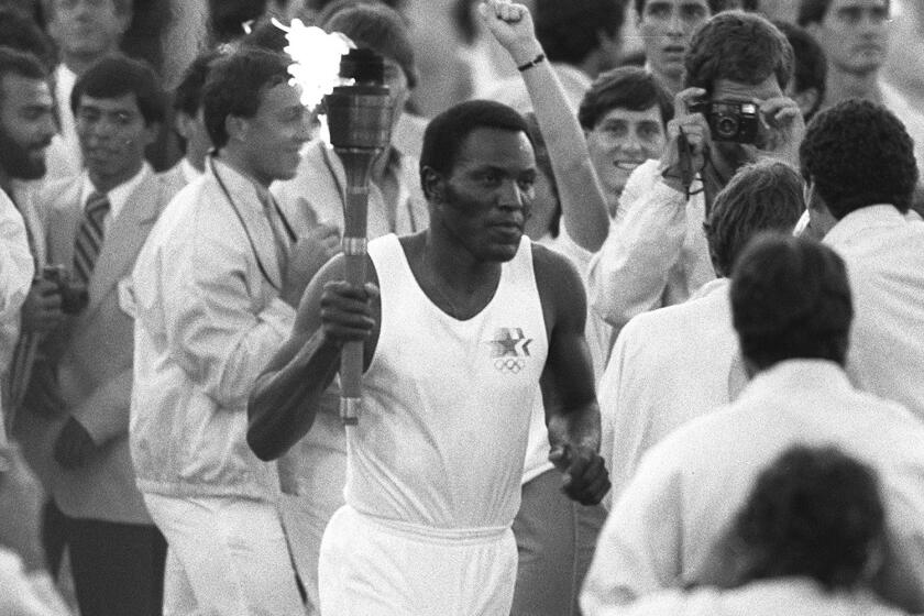 Rafer Johnson runs around the track at the Coliseum before lighting the Olympic flame to open the Los Angeles Summer Olympics on July 28, 1984.