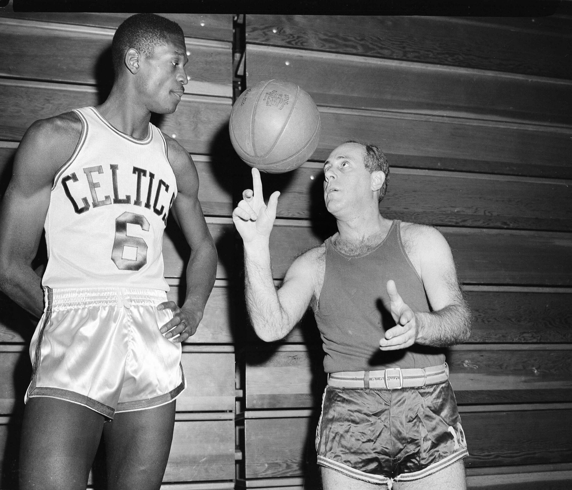 Celtics rookie Bill Russell watches coach Red Auerbach spin the ball on his finger tip.