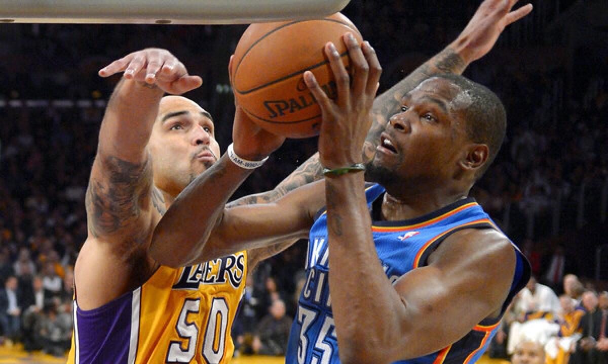 Oklahoma City Thunder forward Kevin Durant, right, puts up a shot in front of Lakers center Robert Sacre during a Lakers' loss on Feb. 13. The Lakers will look to snap their three-game losing streak Sunday against the Thunder.